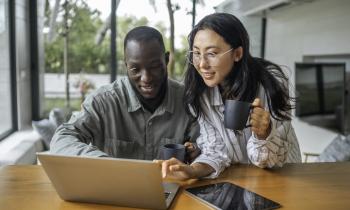 Un jeune couple complète un questionnaire en ligne sur un pc portable dans son salon