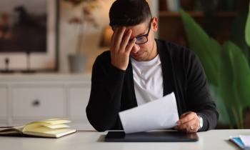 Un homme assis à un bureau lit, inquiet, un courrier qu'il vient de recevoir