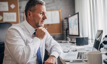 Un homme d'affaires étudie des documents sur son pc portable dans son bureau
