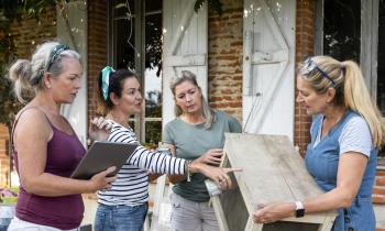 4 femmes échangent devant une maison en briques rouges au sujet des travaux en cours