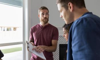 Un professionnel montre à un jeune couple des informations importantes mentionnées sur un document 