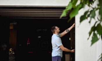 Un homme se tient à l'entrée de son garage, avec la porte ouverte sur l'intérieur
