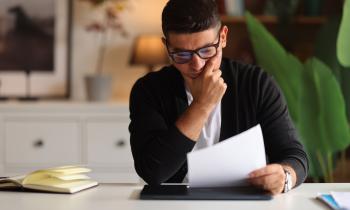 Un homme assis à un bureau découvre le contenu d'un courrier