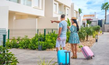 Un homme et une femme avec leurs valises colorées montrent leur lieu de vacances. 