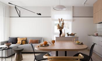 Joli salon avec canapé d'angle gris et table en bois au premier plan. 
