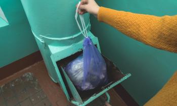 Personne jetant un sac poubelle par la trappe du vide-ordures