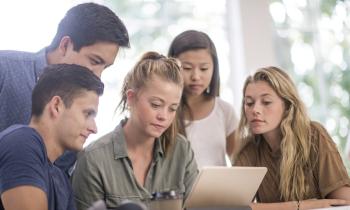 Un groupe de 5 étudiants étudie avec attention un contrat sur une tablette