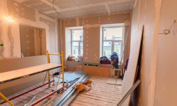 Maison en chantier avec planches de bois posées sur le mur et au sol. 