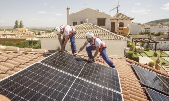 Deux ouvriers du bâtiment installent des panneaux solaires sur le toit d'une maison