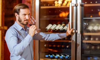 Un homme déguste un vin qu'il vient de choisir dans sa cave à vin réfrigérée
