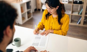 Une jeune femme d'origine asiatique aux cheveux longs signe un contrat lors d'un rendez-vous