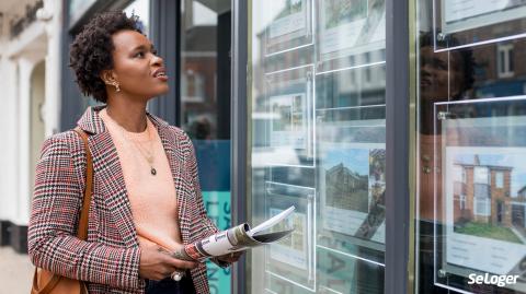 Une femme devant une agence immobilière