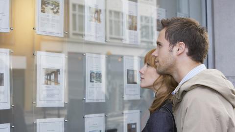 Un couple devant une agence immobilière