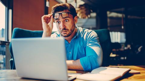 Un homme choqué regarde son ordinateur