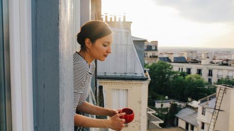Une femme à la fenêtre de son appartement parisien