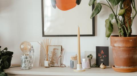 Petite table avec pot de fleurs, bougie, diffuseur et une lampe.