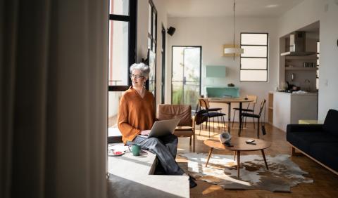 Femme assise au bord de la fenêtre de son salon