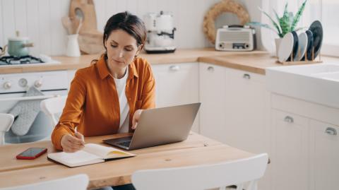 femme concentrée devant son ordinateur dans la cuisine