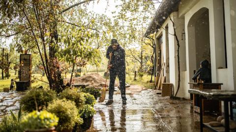 Un monsieur qui balaie sa terrasse sous la pluie