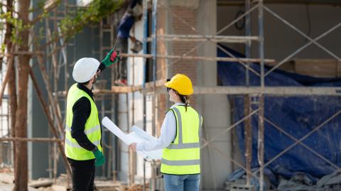 une femme et un homme de dos en tenue de chantier