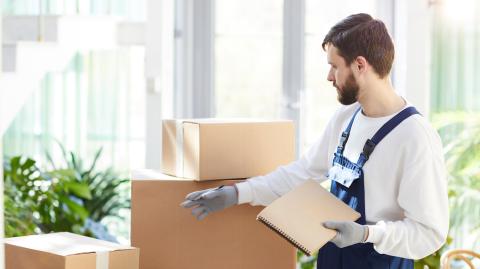 un déméageur devant une pile de cartons en train de faire l'inventaire 