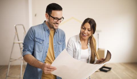 une femme et un homme regarde un document dans un appartement en chantier