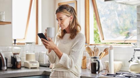 femme cinquante ans dans sa cuisine sur son téléphone