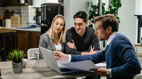 Couples de sourire utilisant un ordinateur avec leur agent d'investissement sur une réunion