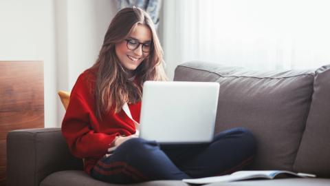 Jeune femme assise sur un canapé avec son ordinateur