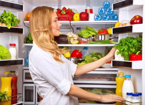 Une femme organisant l'intérieur de son réfrigérateur