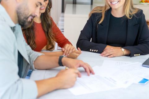 Un homme appose sa signature en bas d'un contrat en présence de deux femmes souriantes