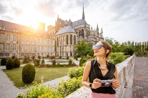 Une femme, un appareil photo à la main, devant la Cathédrale de Reims