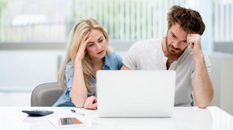 Un homme et une femme semblent dépités, assis côte à côte devant leur ordinateur