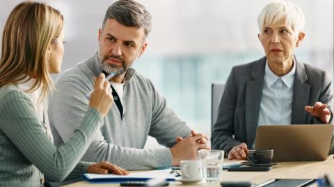 Un couple échange autour d'un bureau lors d'un rendez-vous avec sa banquière