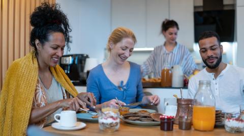 Quatre personnes prennent le petit-déjeuner ensemble autour d'une table à leur domicile