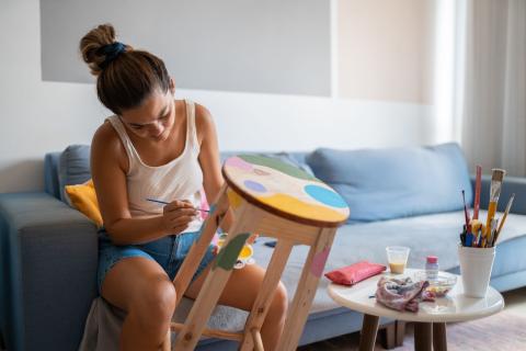 Jeune femme peint un tabouret en bois