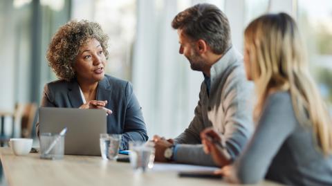 Un couple échange avec sa conseillère bancaire, assis à un bureau