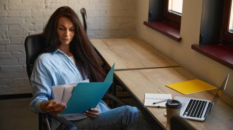 Une femme étudie avec attention un document papier qu'elle tient entre ses mains