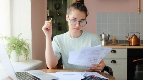 Une chose femme assise à un bureau fait des calculs, en étudiant divers documents au format papier