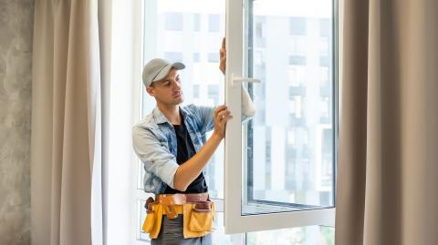 Un artisan termine l'installation d'une nouvelle fenêtre dans un logement. ©GettyImages