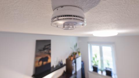 Un détecteur de fumée est fixé au plafond dans une pièce de vie