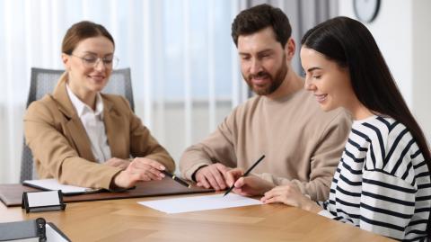 Un jeune couple signe les documents relatifs à l'achat de son nouveau logement chez le notaire