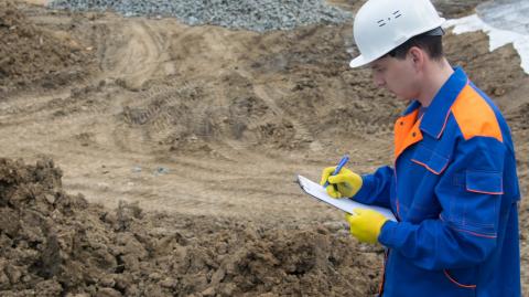 Un ingénieur muni d'un casque de chantier réalise l'étude géotechnique d'un terrain