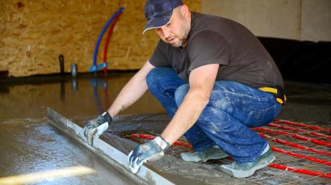Un artisan procède à la pose d'un sol en béton en intérieur
