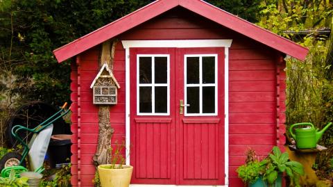 Petite maisonnette en bois rouge servant d'abri de jardin, en limite de propriété