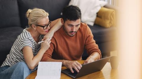 Un couple effectue des recherches sur un ordinateur portable, dans son salon