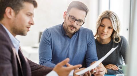 Un couple étudie des documents avec son banquier lors d'un rendez-vous