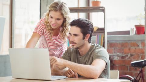 Un jeune couple étudie avec attention des dossiers sur un ordinateur portable