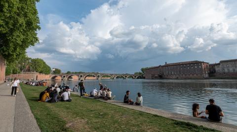Des étudiants sont assis sur l'herbe sur les berges de la Garonne, à Toulouse, par une journée ensoleillée