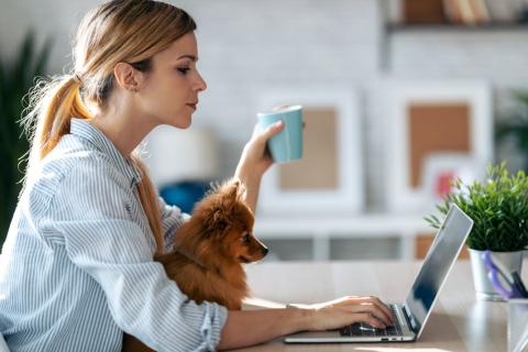femme tient une tasse et recherche à faire un investissement immobilier devant son ordinateur